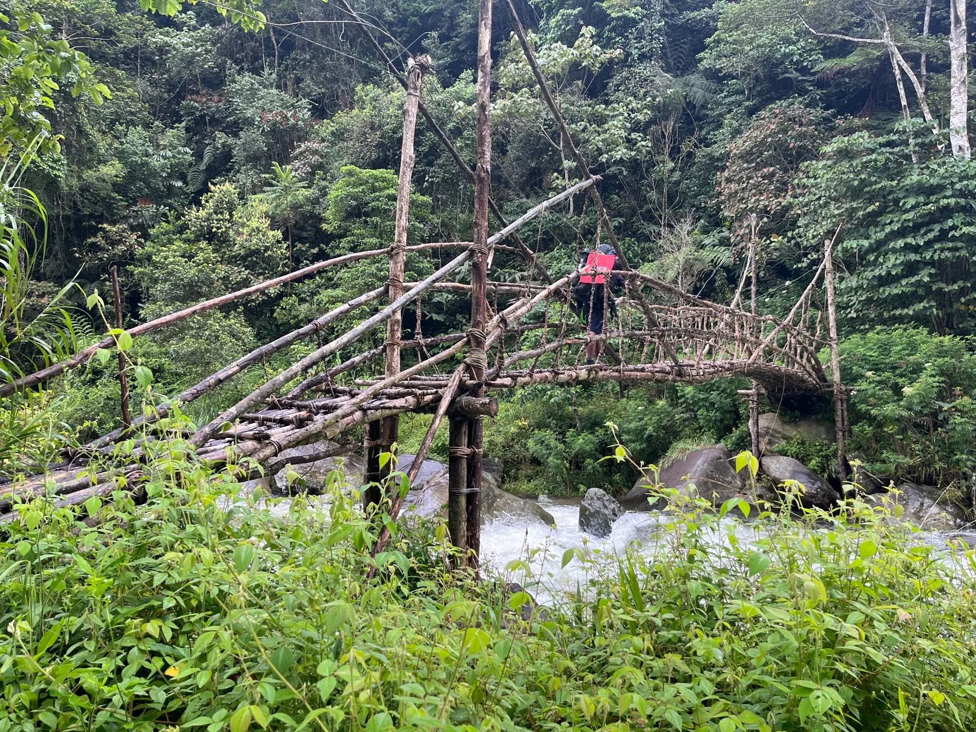 A traditional timber bridge crossing a fast-flowing river on the Kokoda Track